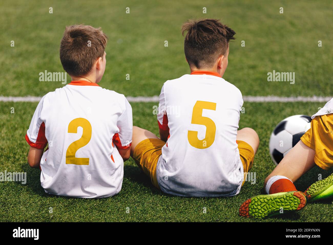 Boys in Soccer Jerseys with Golden Player Numbers on Back. Football Team Sitting on Sideline. Group of Young Boys in School Sports Team Stock Photo
