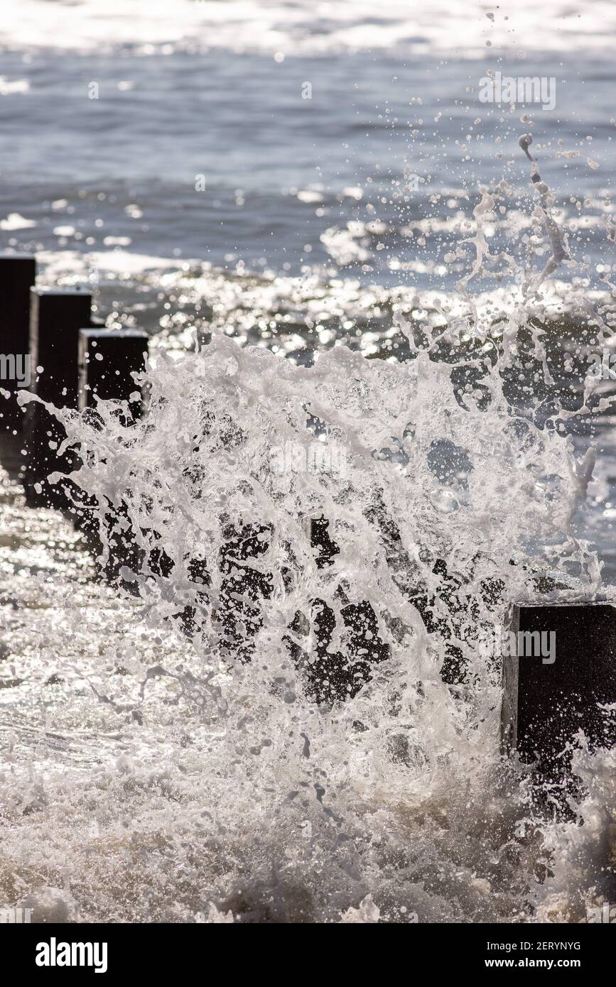 Waves break against the groyne at the beach at Fisherman’s Walk, Southbourne, Bournemouth on a beautifully sunny February day during the COVID-19 coro Stock Photo