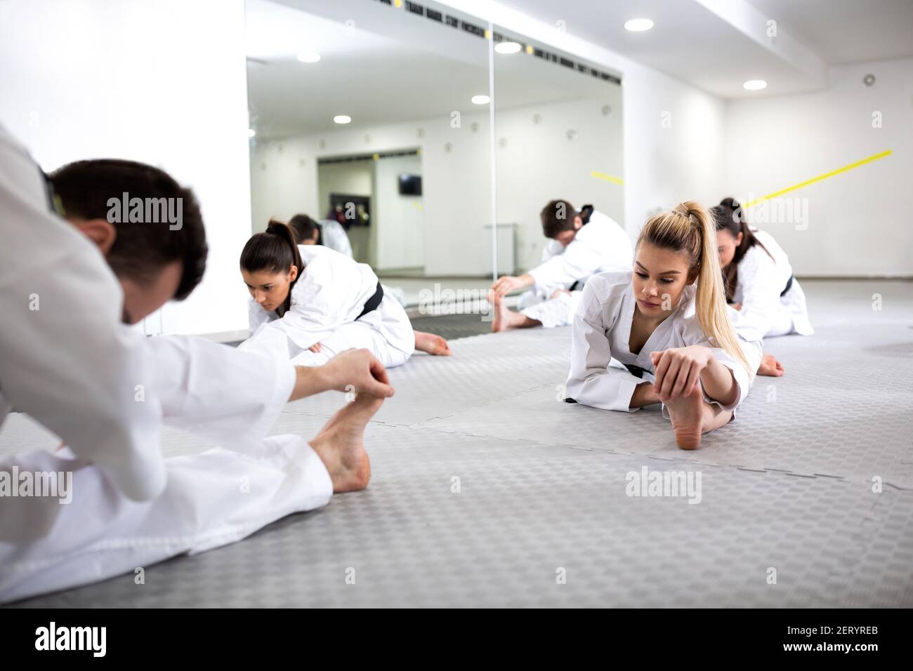 Martial artists doing leg splits while warming up for taekwondo