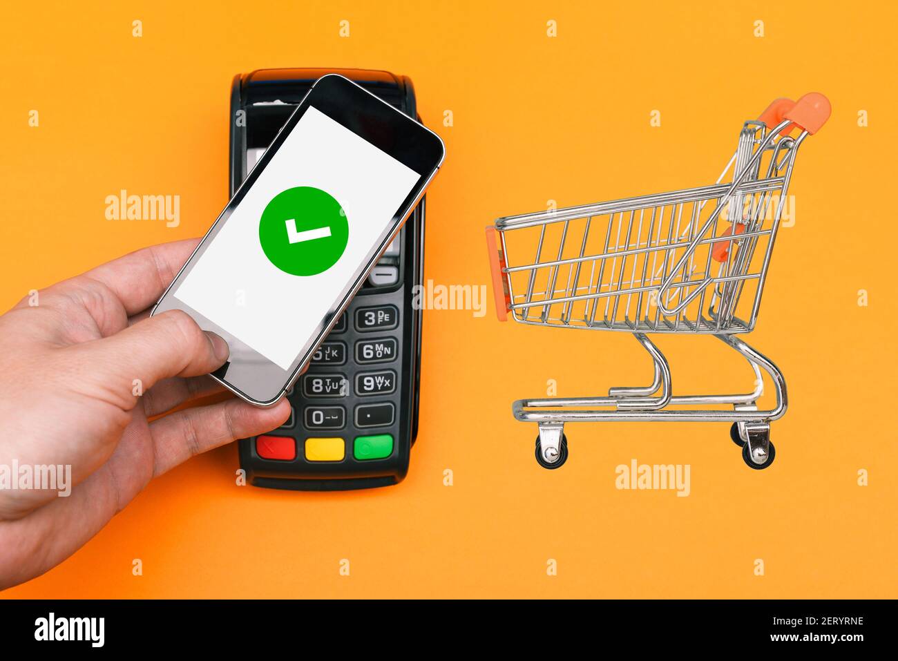 Electronic payment Pos terminal and shopping trolley from the mall. Successful payment with confirmation on the smartphone screen. Contactless method Stock Photo