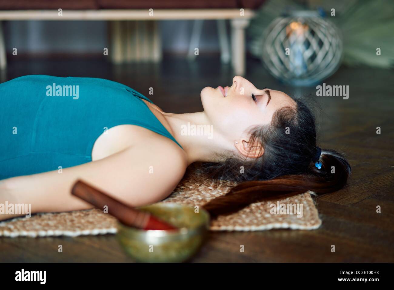 Young woman resting after work out lying on carpets performing Shavasana or Corpse Dead position, body and mind relaxation concept Stock Photo