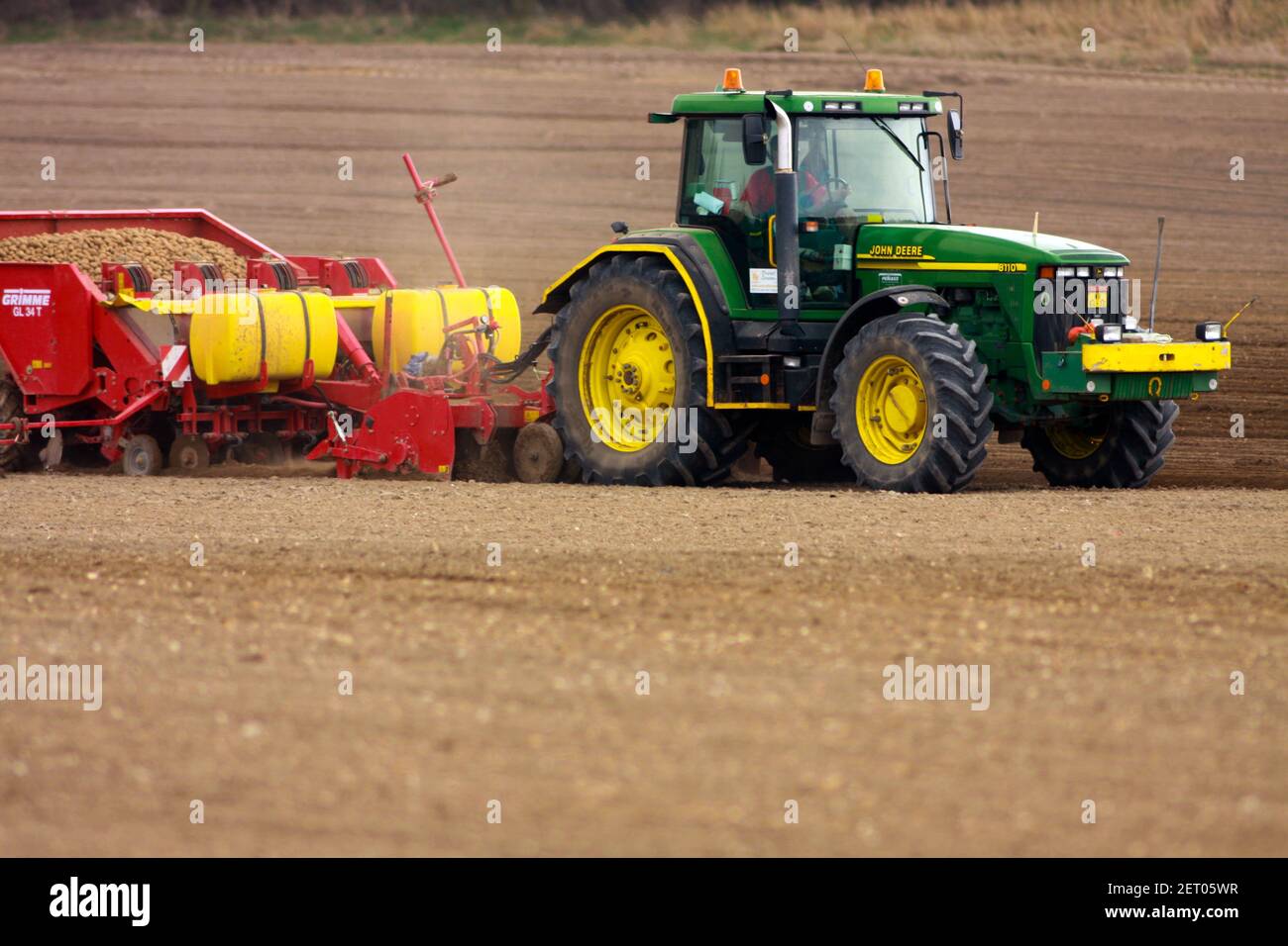 John Deere tractor potato planter sowing new crop into spring fine soil, farming machinery Stock Photo