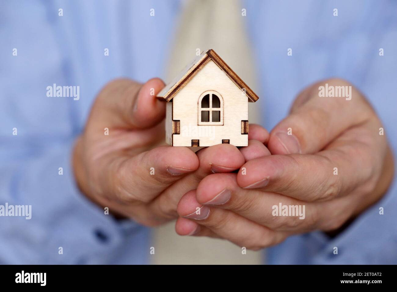 Real estate agent, wooden house in male hands. Man in office clothes with house model, purchase or rental home Stock Photo