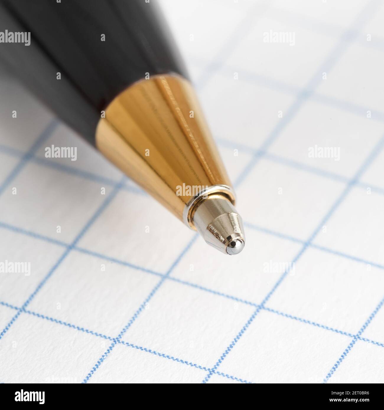 Close up of the tip of a ballpoint pen on the background of a sheet of checkered paper Stock Photo