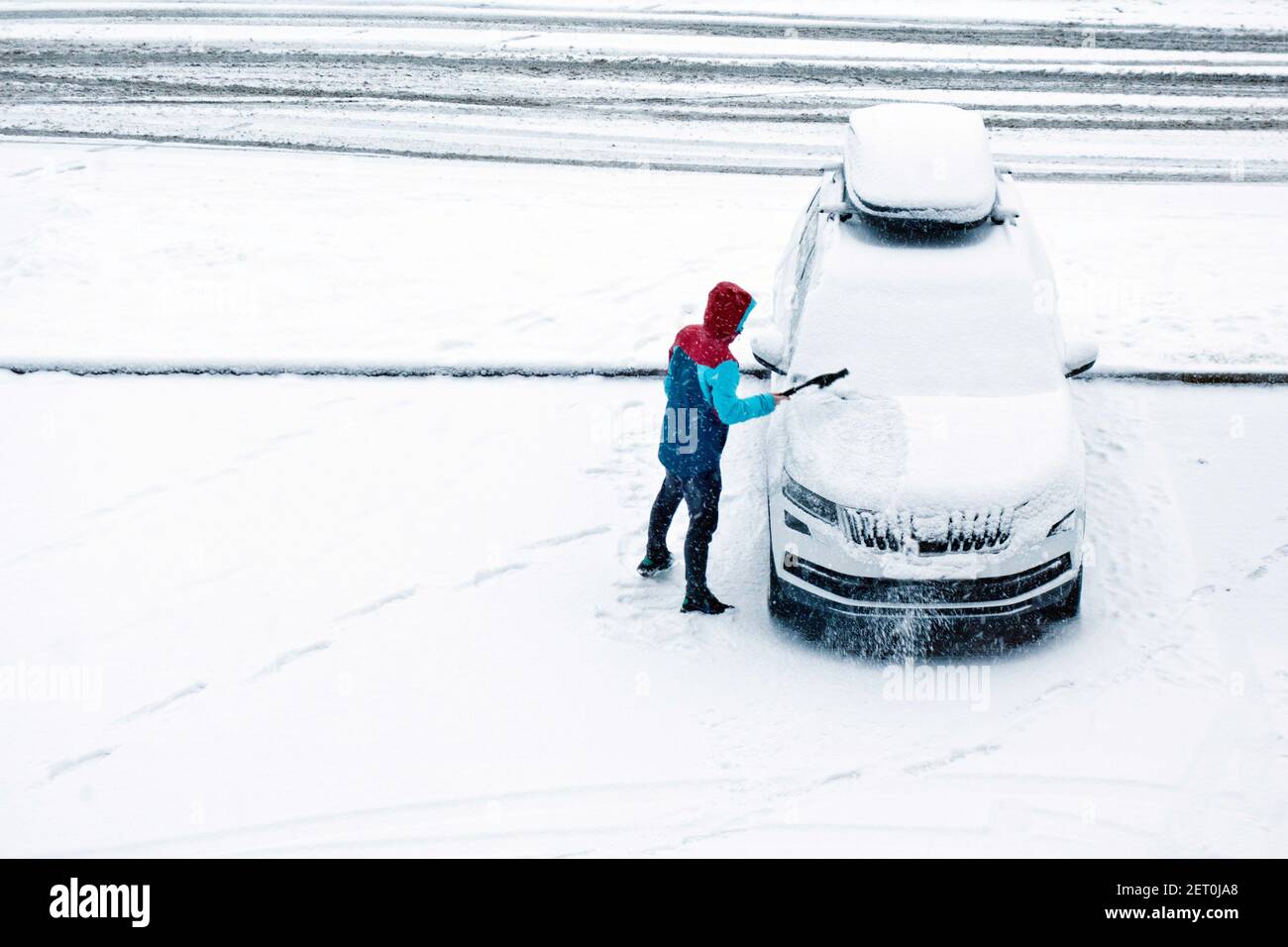 man removing snow from the windshield of his own car Stock Photo