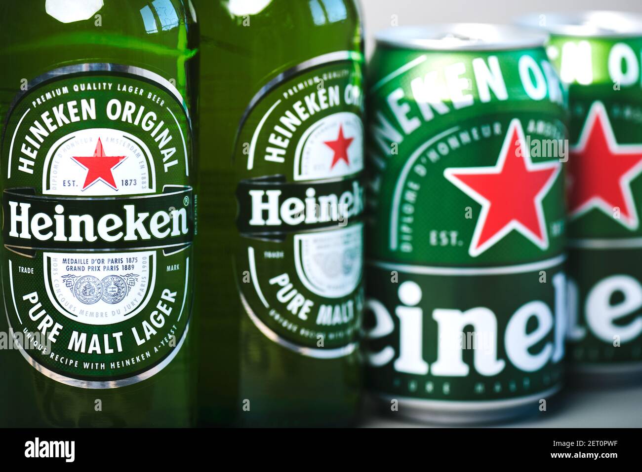 Heineken lager beer bottles and Heineken beer aluminum cans on green background Stock Photo