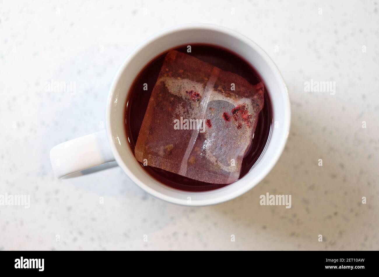 strawberry fruit teabag in white mug on kitchen worktop Stock Photo