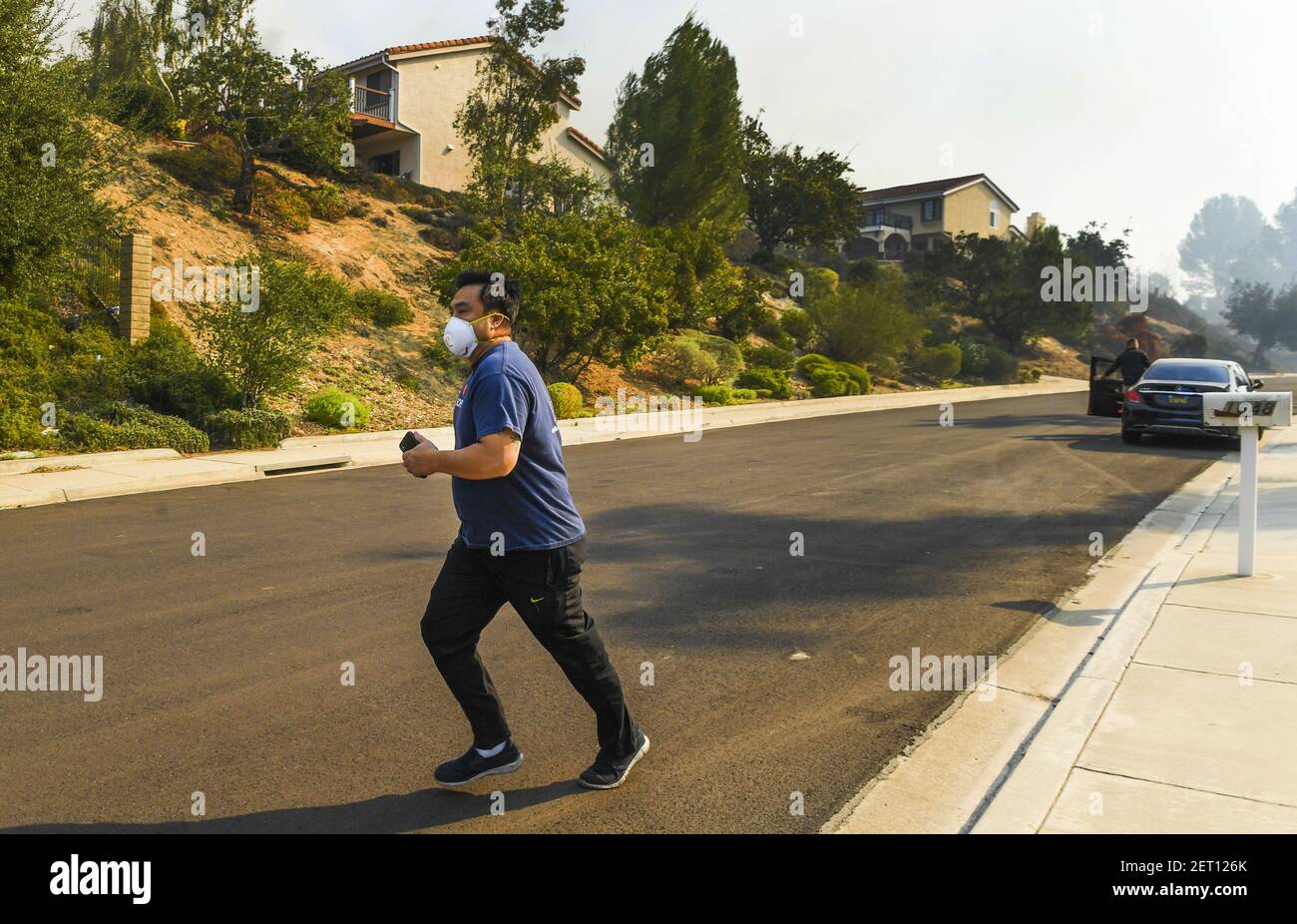 November 9, 2018; Thousand Oaks, CA, USA: A resident wearing a breathing mask runs down Shadow Oaks Place as smoke from flames in a hill above the homes fills the neighborhood. Some residents decided to leave their homes as firefighters kept a watchful eye on the fire. Mandatory Credit: Robert Hanashiro-USA TODAY/Sipa USA Stock Photo