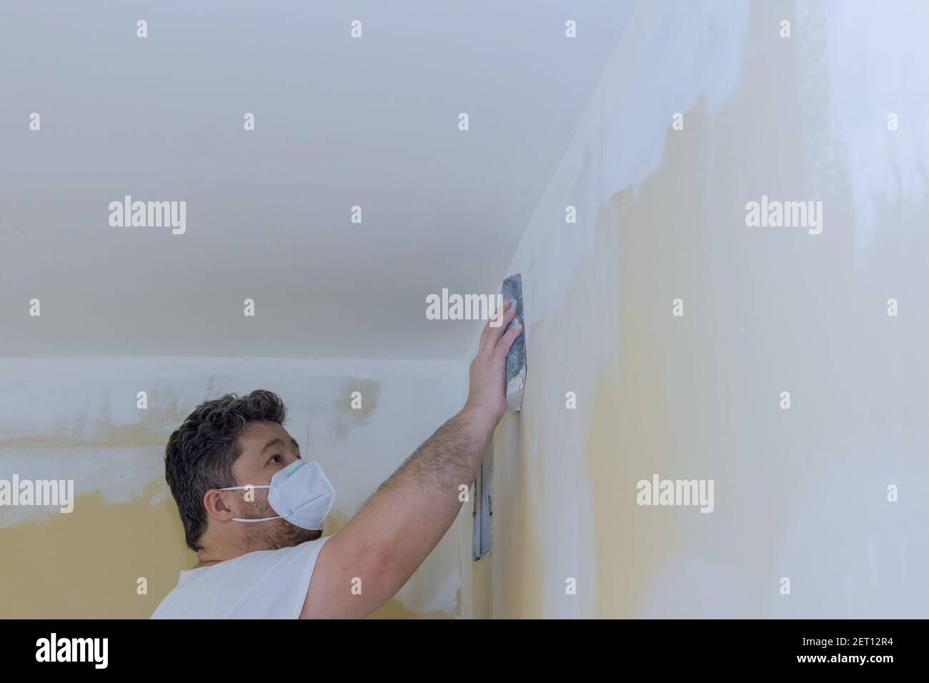Contractor using sand trowel sanding the the plaster plasterboard