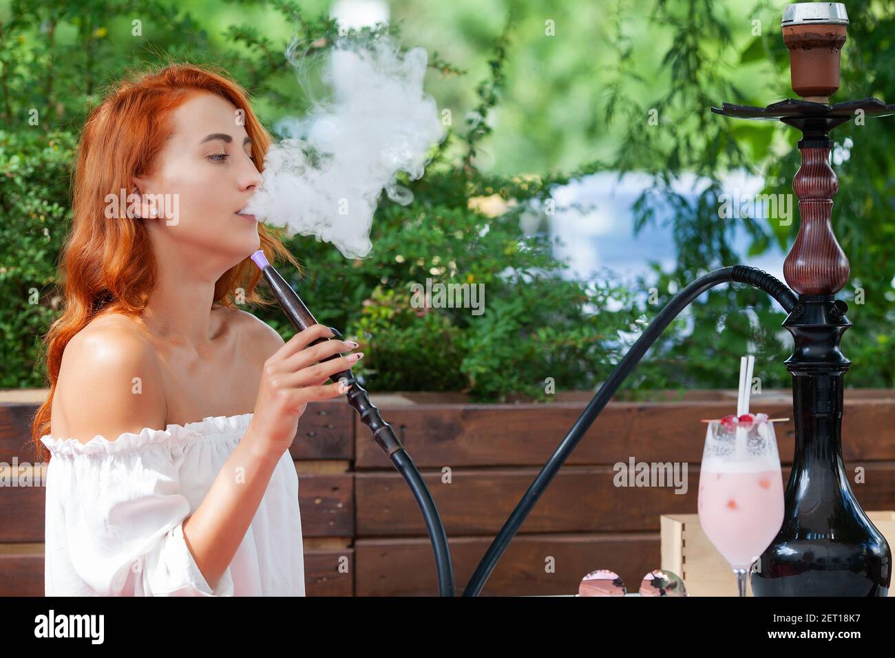 Young women smoke a hookah in a cafe on the street Stock Photo Alamy