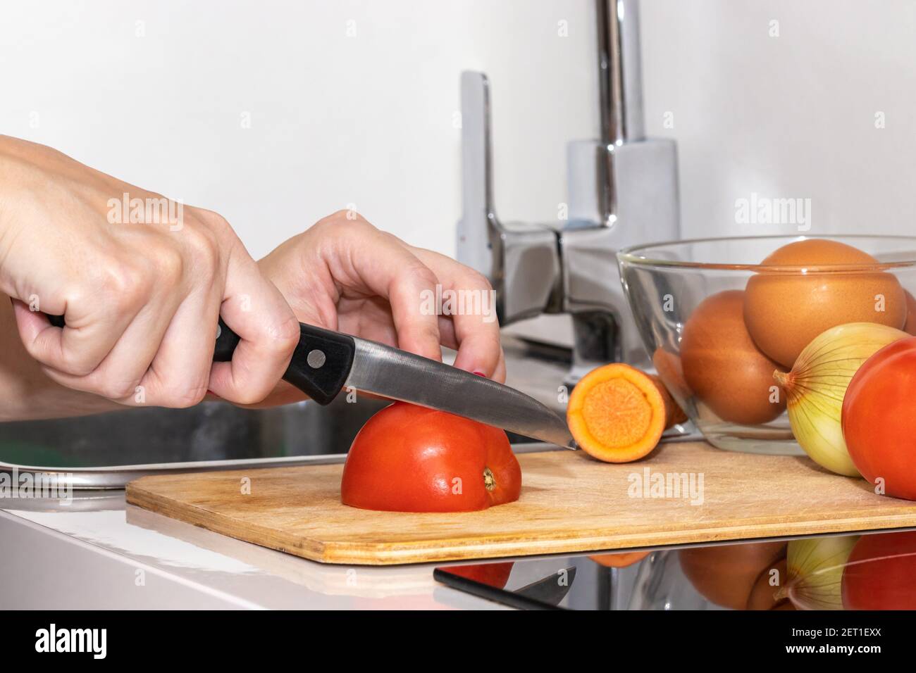 https://c8.alamy.com/comp/2ET1EXX/womans-hands-cutting-tomato-behind-fresh-vegetables-2ET1EXX.jpg