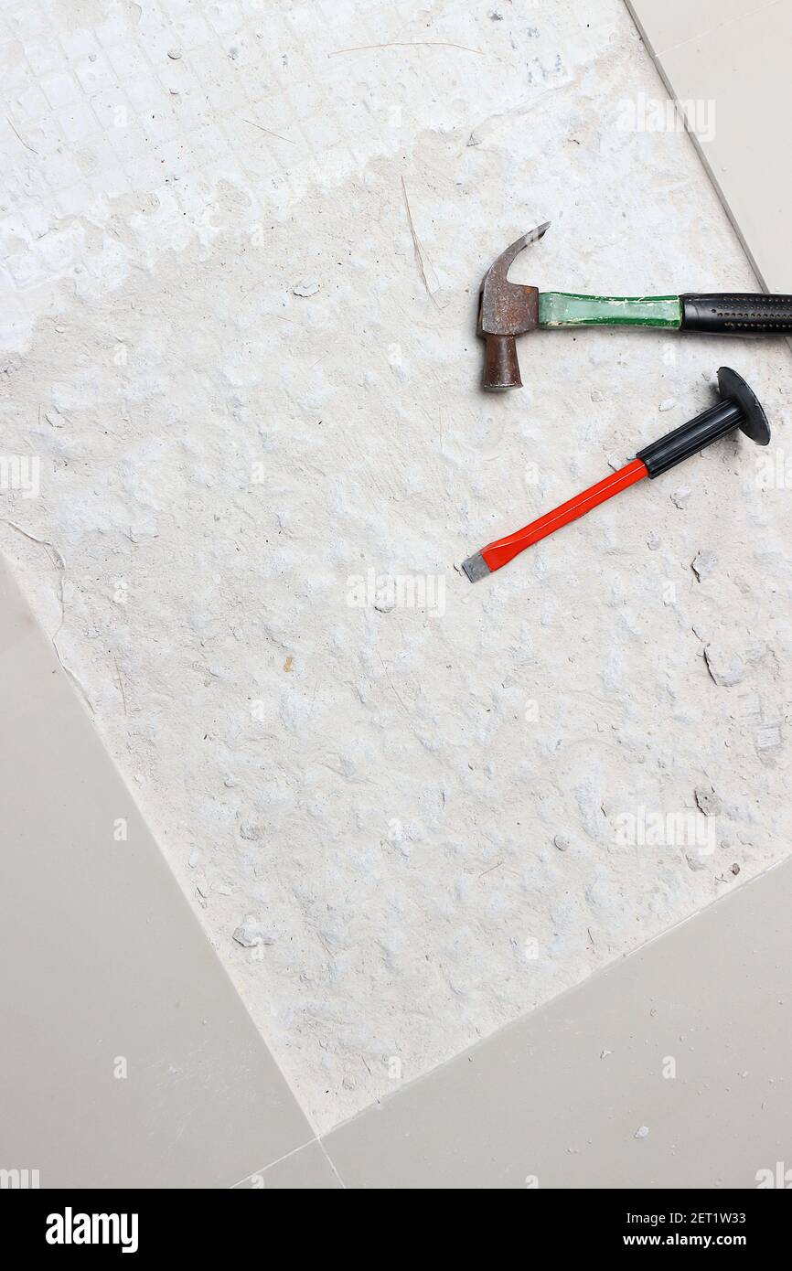 A hammer and a chisel hammer for drilling concrete is placed beside the area being newly tiled. Stock Photo
