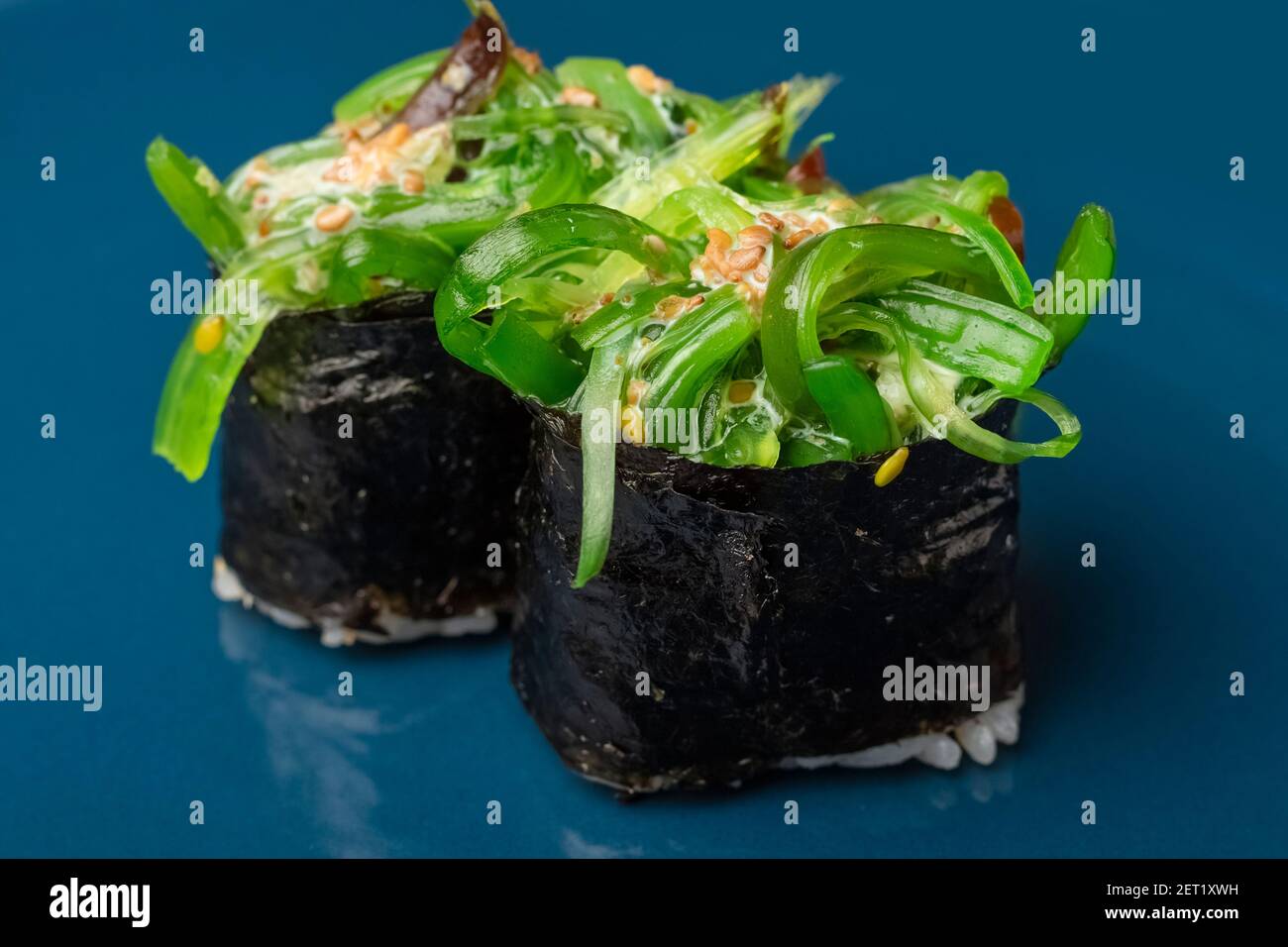 Two chukka gunkan seaweed sushi rolls on a blue plate. Serving Japanese food Stock Photo