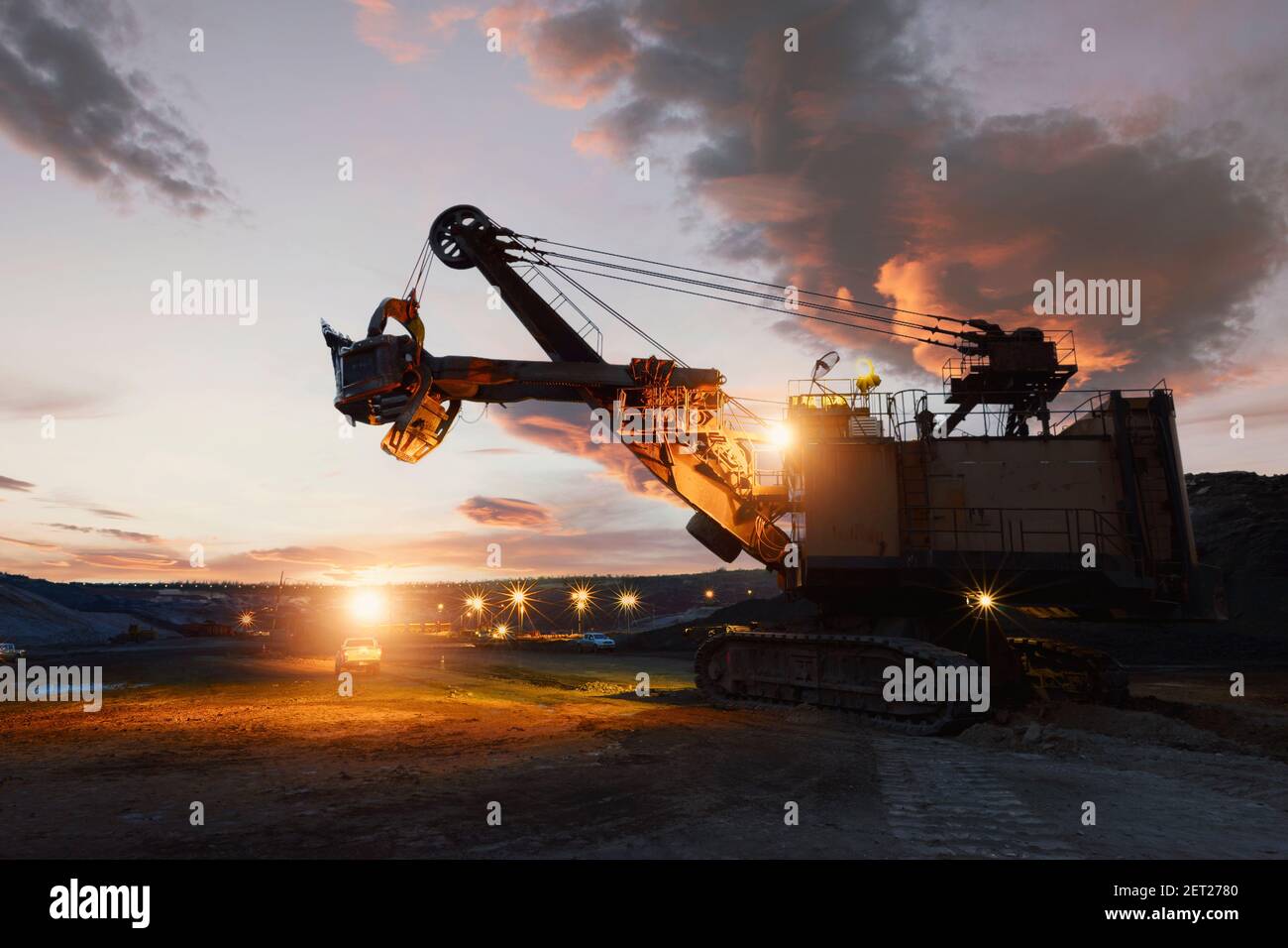 Silhouette of a mechanical digger at an iron ore mine at sunset, Thailand Stock Photo