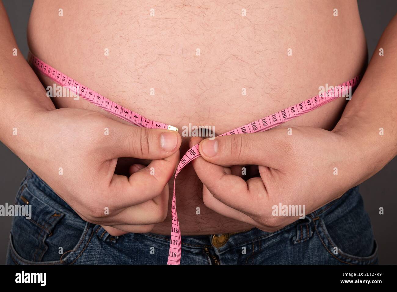 obesity a man measures his big belly with a centimeter,wrong lifestyle Stock Photo