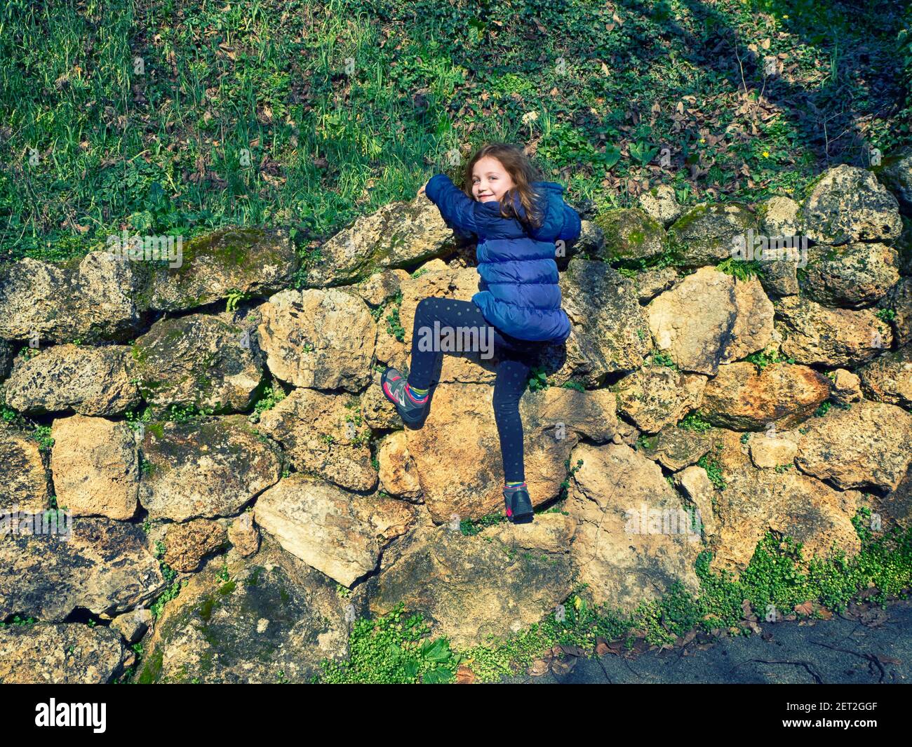 Smiling girl climbing a stone wall, Italy Stock Photo Alamy