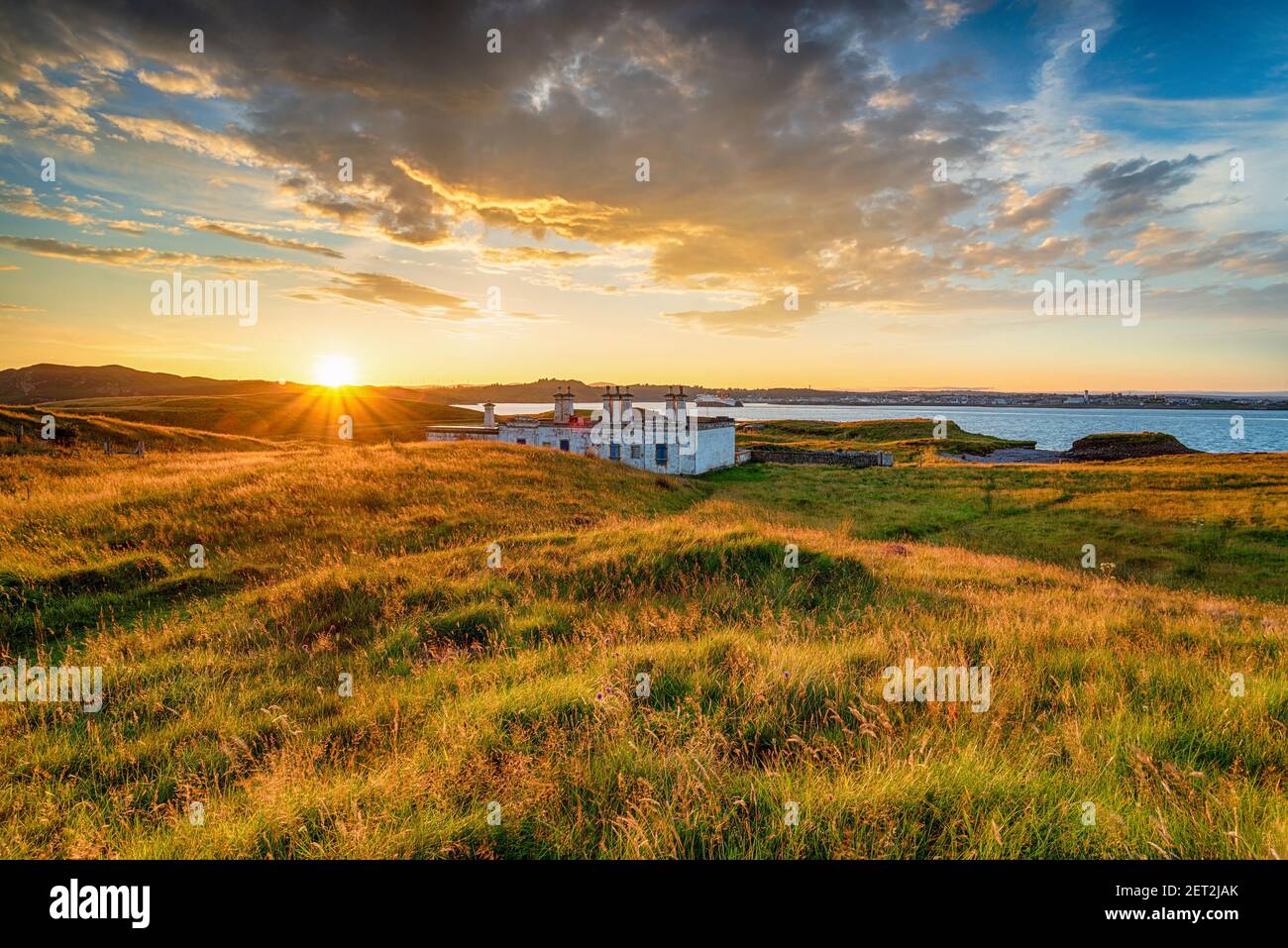 Dramatic sunset over the old coastguard cottages at Arnish Point on the entrance to Stornoway harbour on the Ilse of Lewis in the Western Isles of Sco Stock Photo