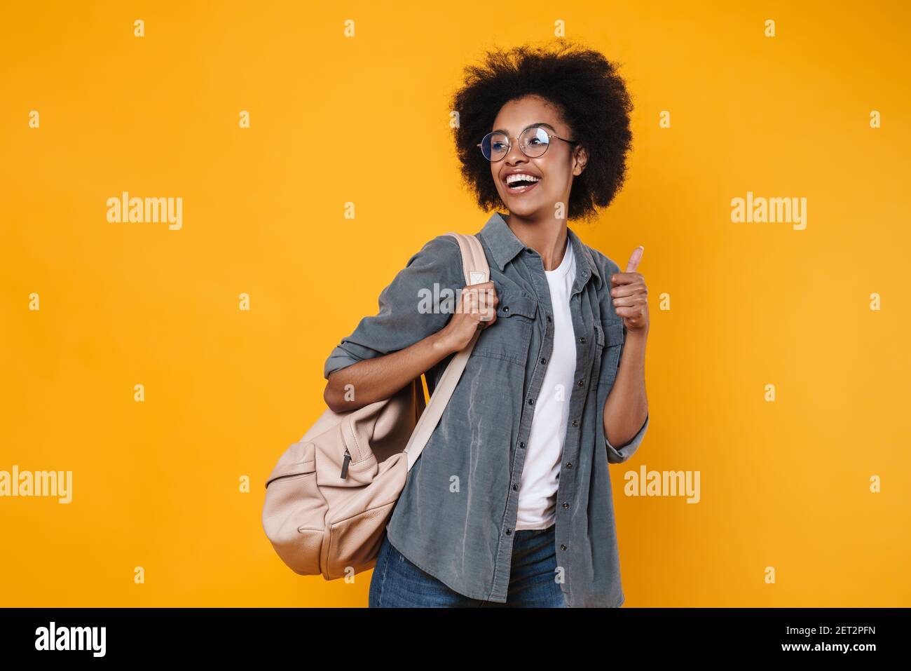 Joyful african american girl in eyeglasses showing thumb up at camera ...