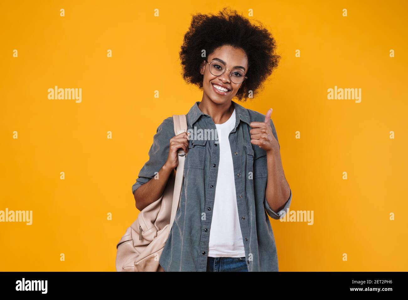 Joyful african american girl in eyeglasses showing thumb up at camera ...