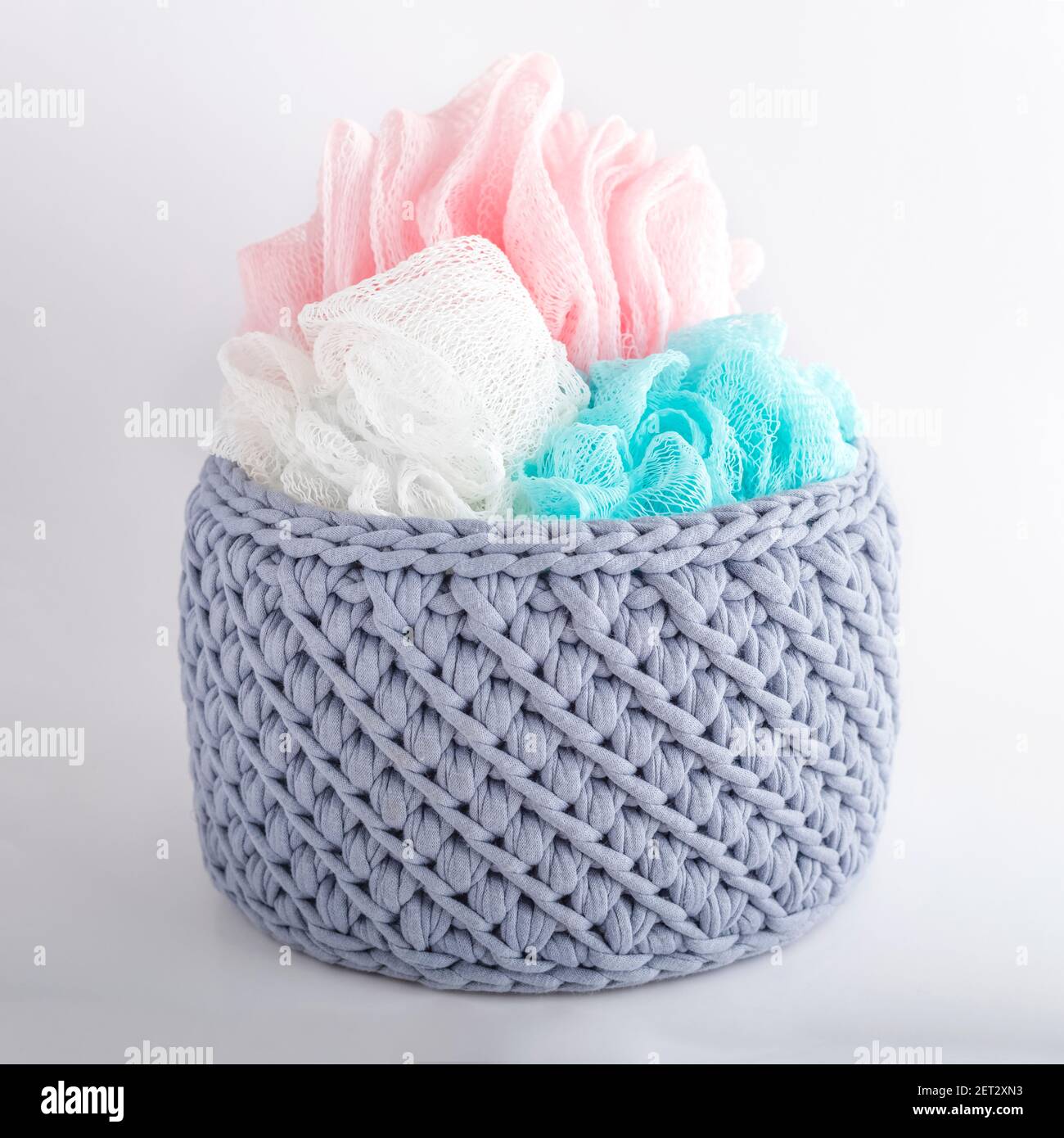 gray handmade basket with colored washcloths. texture of knitted fabric braids Stock Photo
