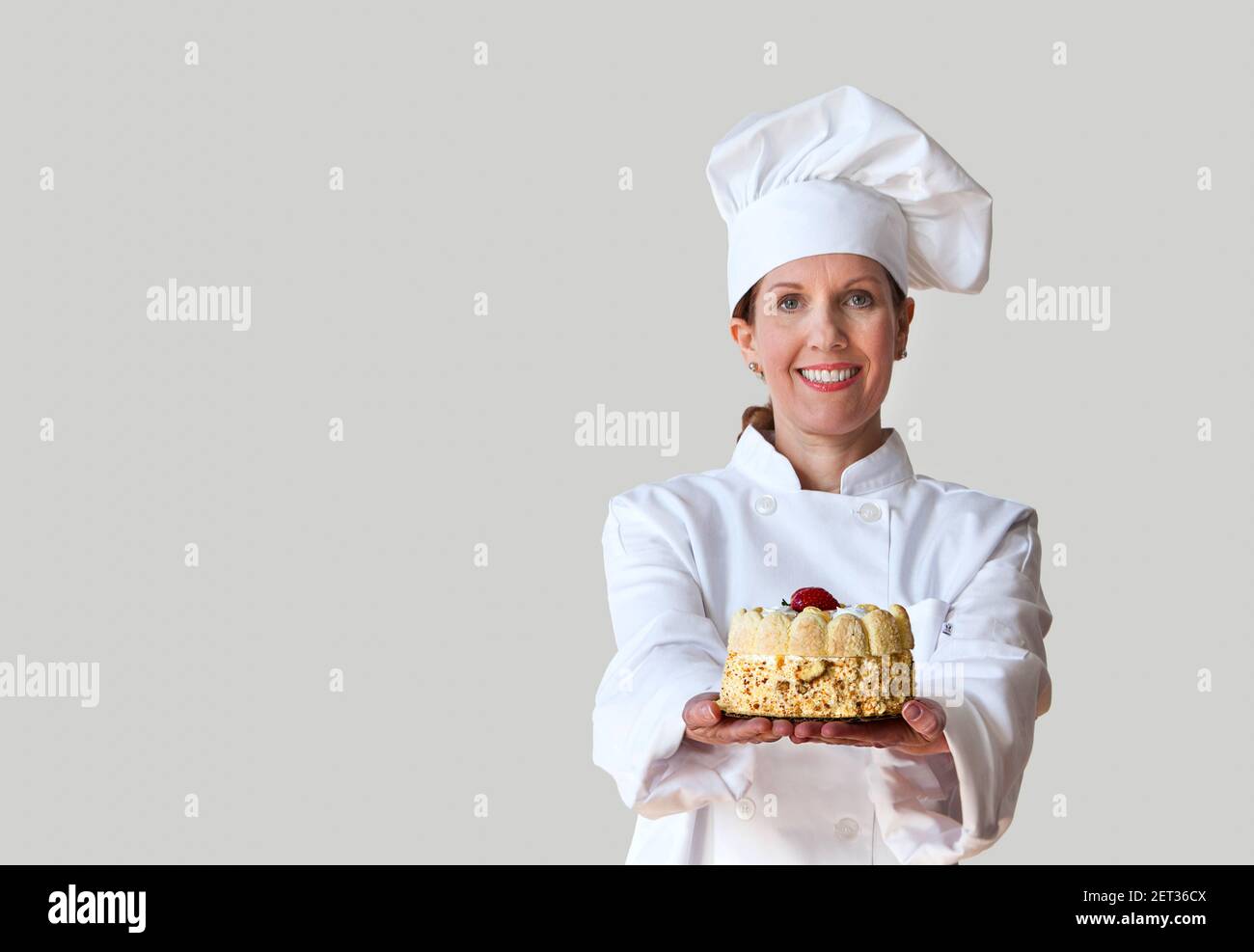 Chef holding a cake wearing a clean white chef uniform. Stock Photo