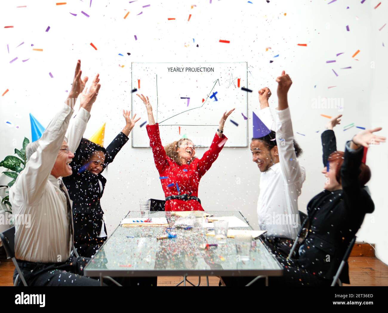Ecstatic business people celebrate an excellent yearly projection with party hats and confetti. Humorous business concept. Stock Photo