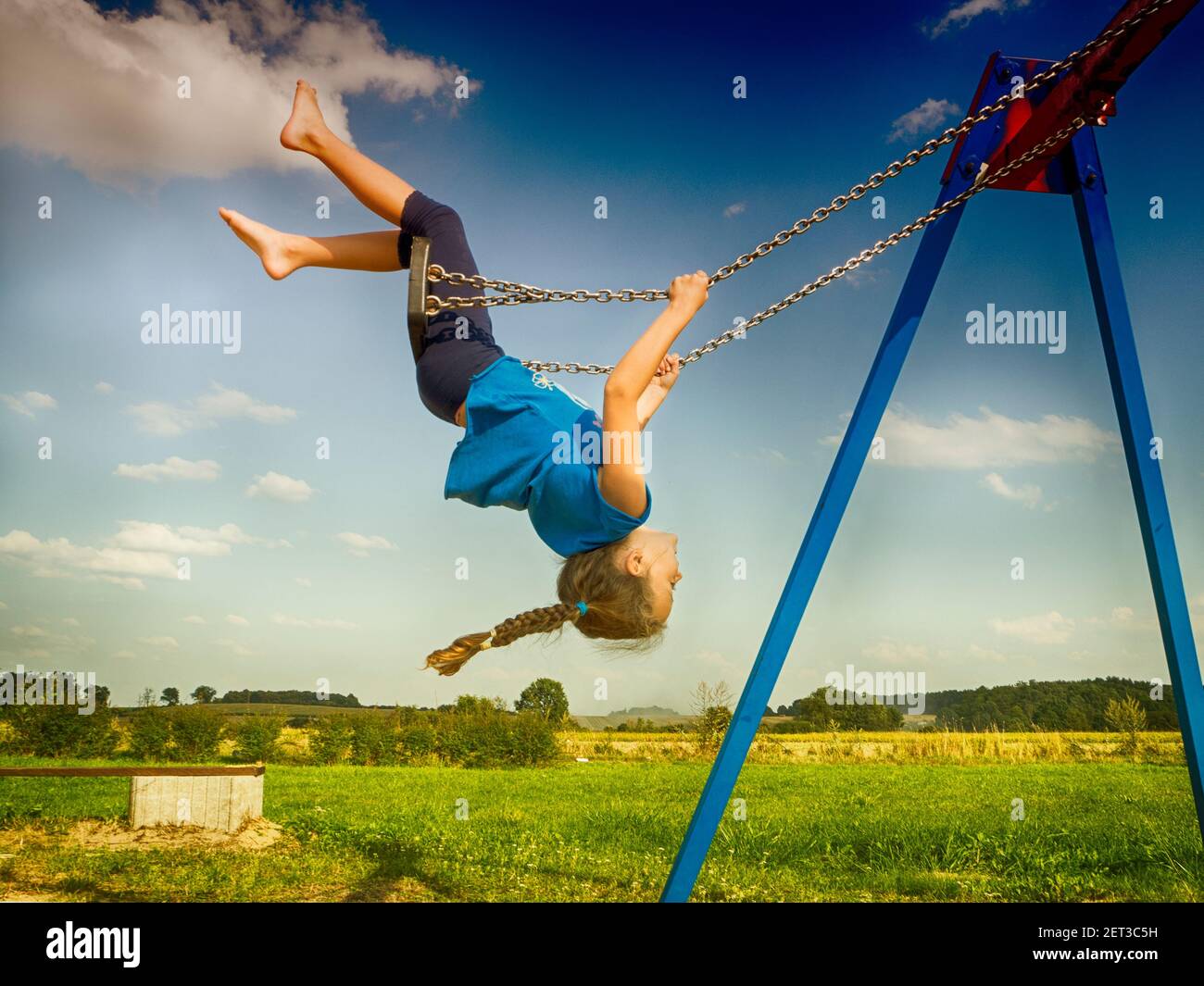 Upside down girl swinging on a swing in a playground, Poland Stock Photo