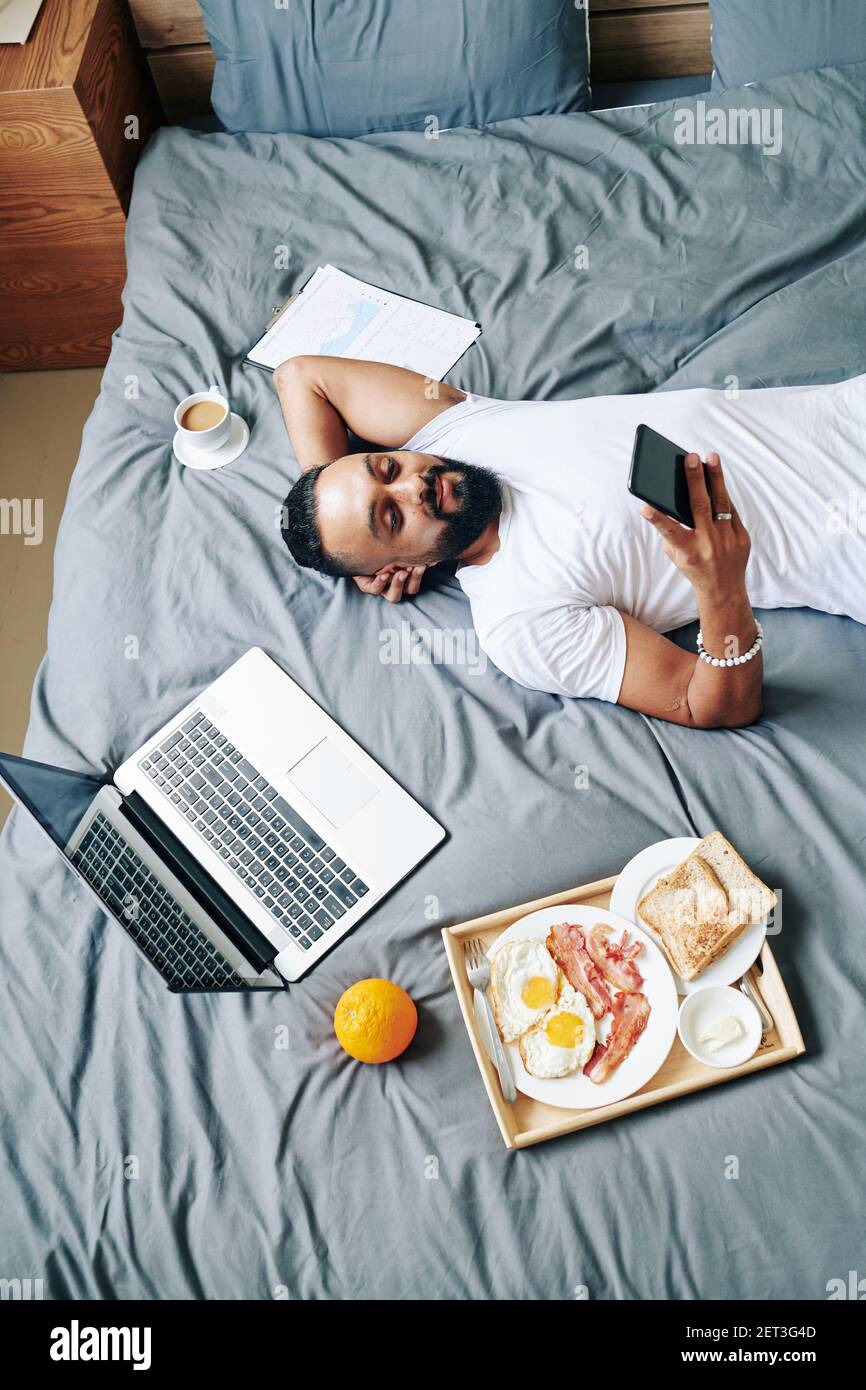 Man resting on bed Stock Photo - Alamy