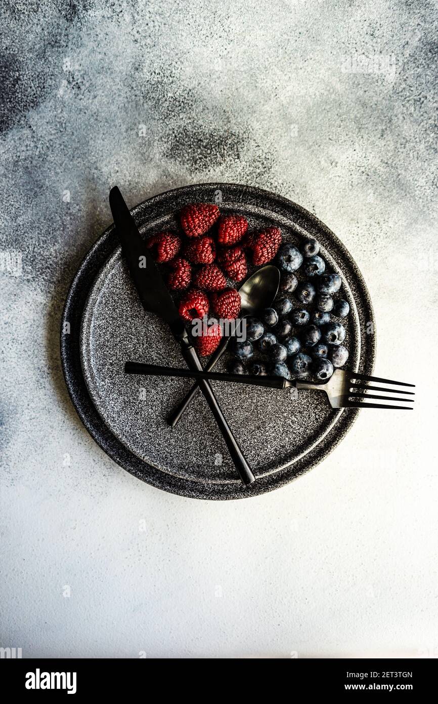Blueberries and raspberries arranged on a plate to convey intermittent fasting concept Stock Photo