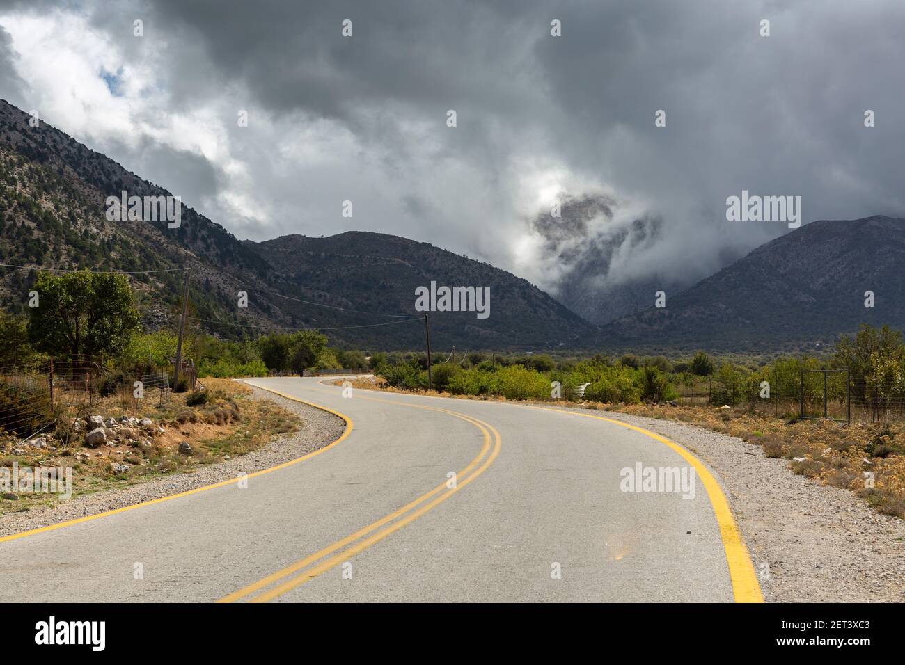 Dramatic clouds over a road and mountainous landscape near the Samaria Gorge trailhead, Crete, Greece Stock Photo