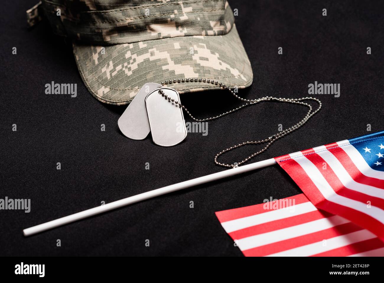 Close up view of dog tags, cap and american flag on black background ...