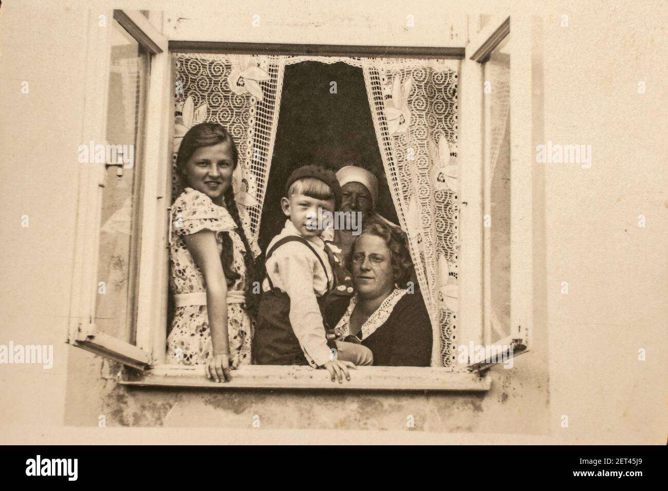 Latvia - CIRCA 1930s: A family sitting together in a window sill group shot. Children lived in a three generation family household. Vintage art deco e Stock Photo