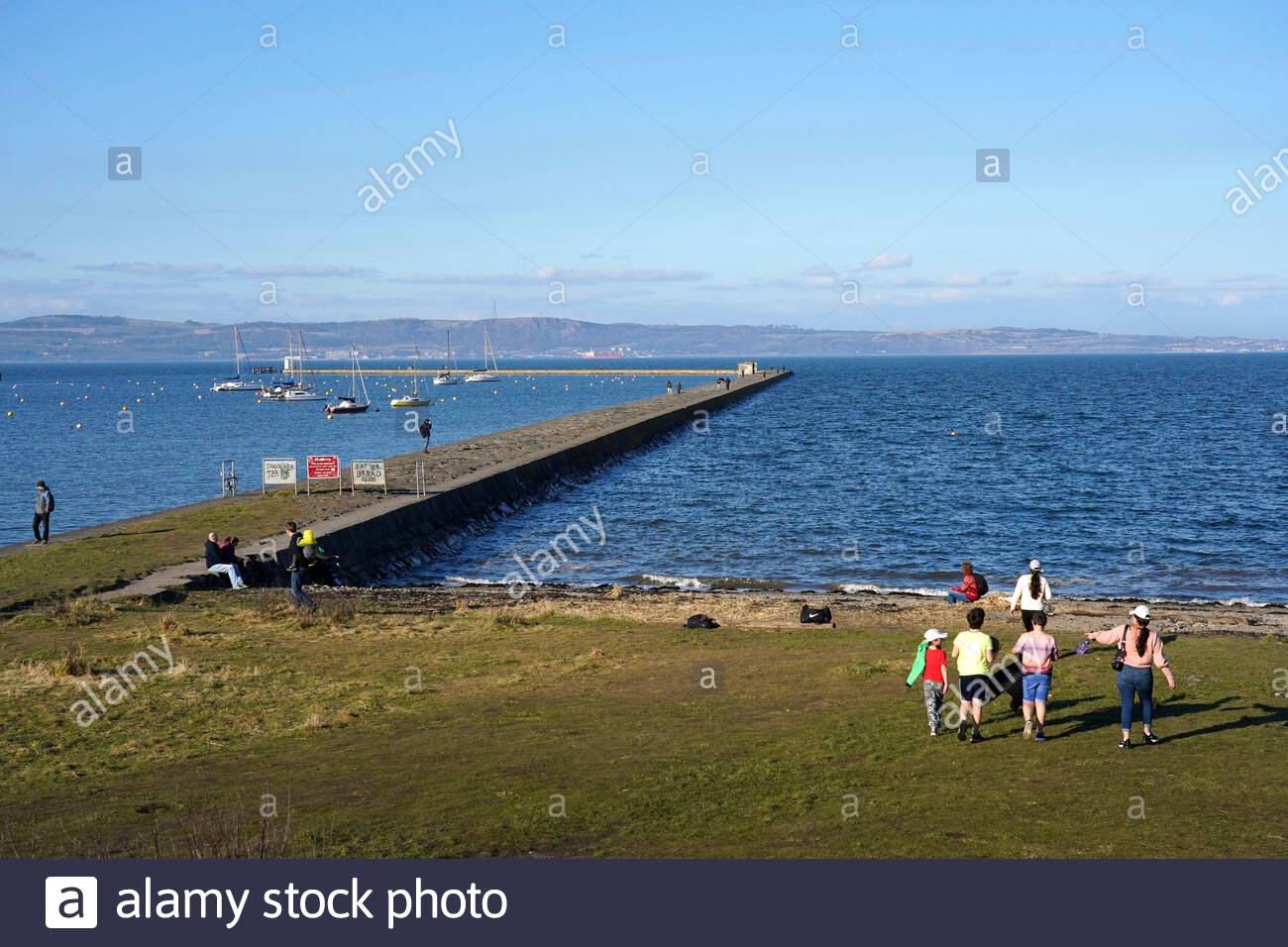 Edinburgh, Scotland, UK. 1st Mar 2021. People enjoying the outdoors at Wardie Bay waterfront, Granton harbour and breakwater on a cool and sunny afternoon. View over the Forth estuary looking North towards Fife. Credit: Craig Brown/Alamy Live News Stock Photo