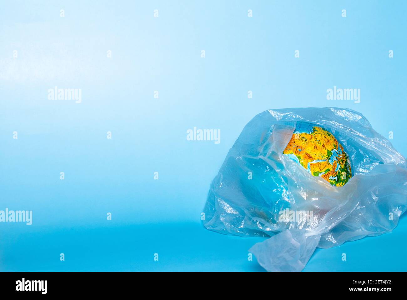 The concept of ecology. Globe in plastic wrap on a blue background