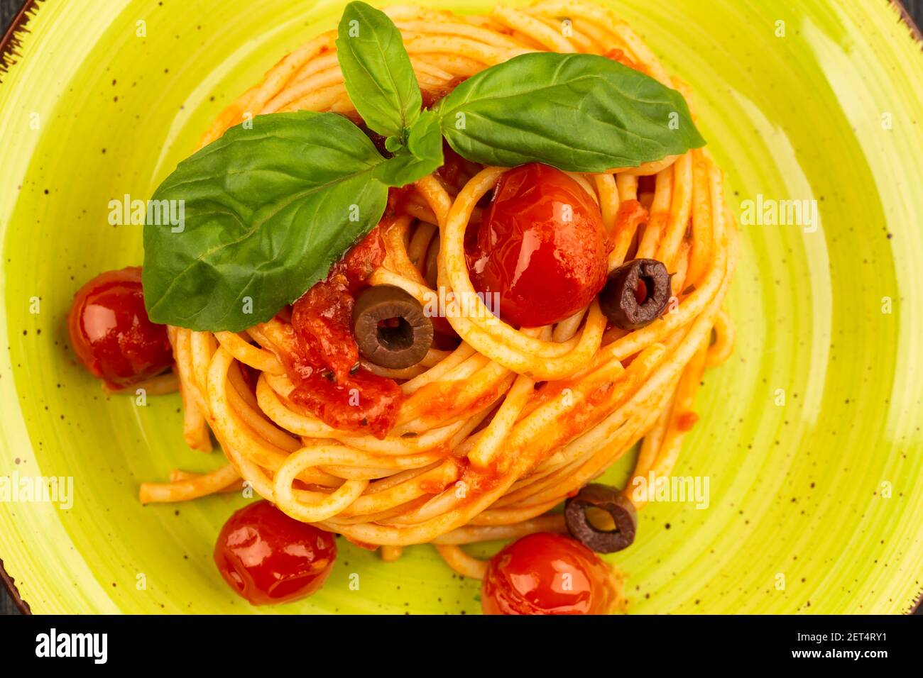Pasta spaghetti Napoli or Napolitana on green plate top view, flat lay. Italian cuisine. Stock Photo