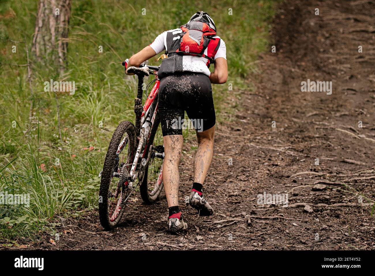 rider cyclist with mountain bike uphill climb on forest trail Stock Photo