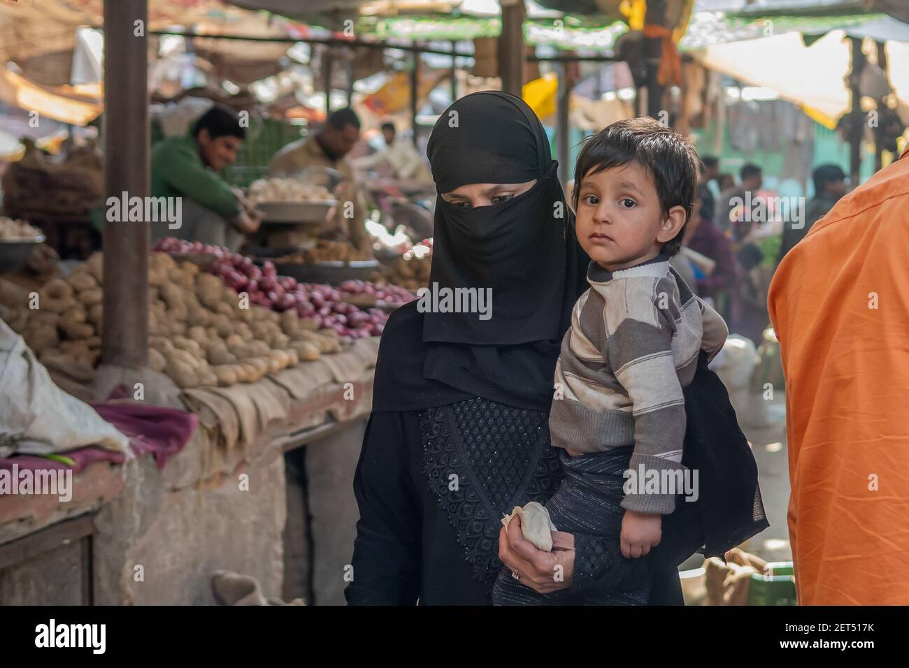 Jaipur, India. 09-05-2018. Muslim woman with wail dress in black carrying her child is walking in the local market in the center of Jaipur. Stock Photo