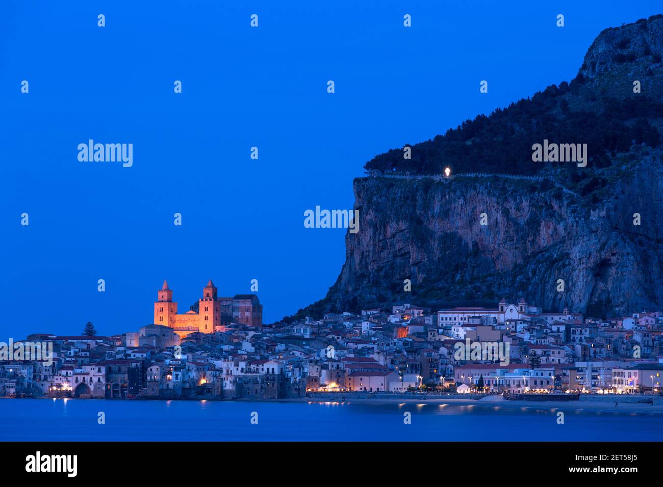 Italy, Sicily, Cefalu, a seaside view of the town illuminated at evening with the Rocca a Norman medieval fortress Stock Photo
