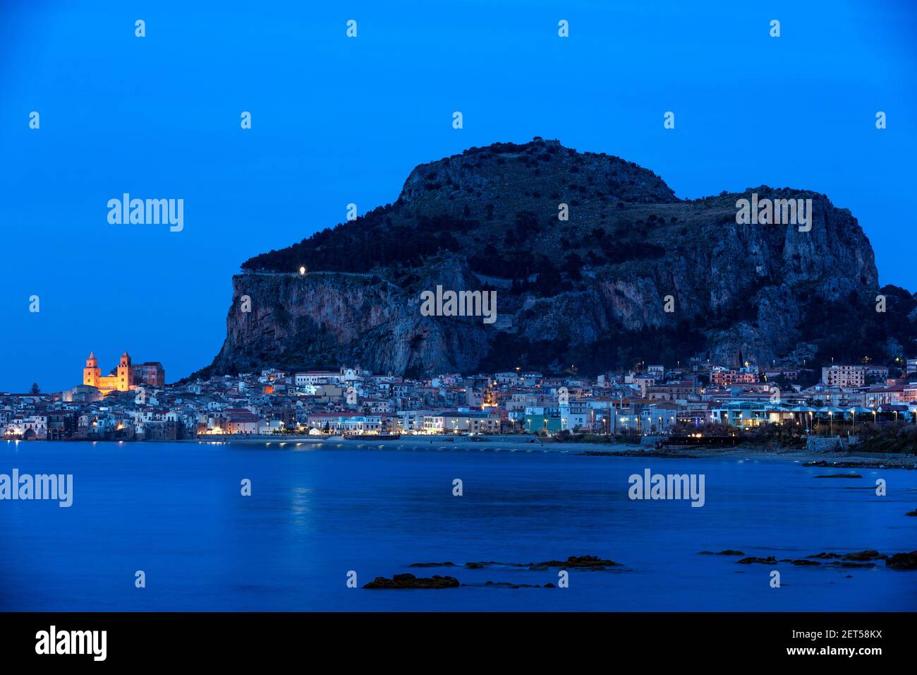 Italy, Sicily, Cefalu, a seaside view of the town illuminated at evening with the Rocca a Norman medieval fortress Stock Photo