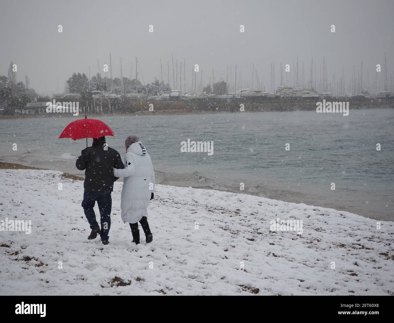 Couple with a red umbrella walking by the beach in a snowstorm, near Athens,  Greece , in February Stock Photo - Alamy