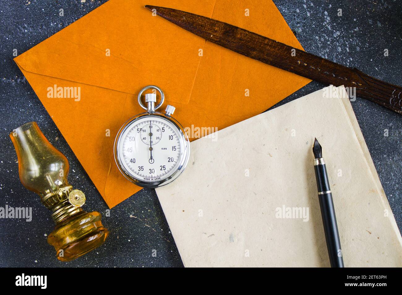 A closeup top view of antique vintage objects set with old pocket clock, paraffin lamp, and letter writing supplies Stock Photo