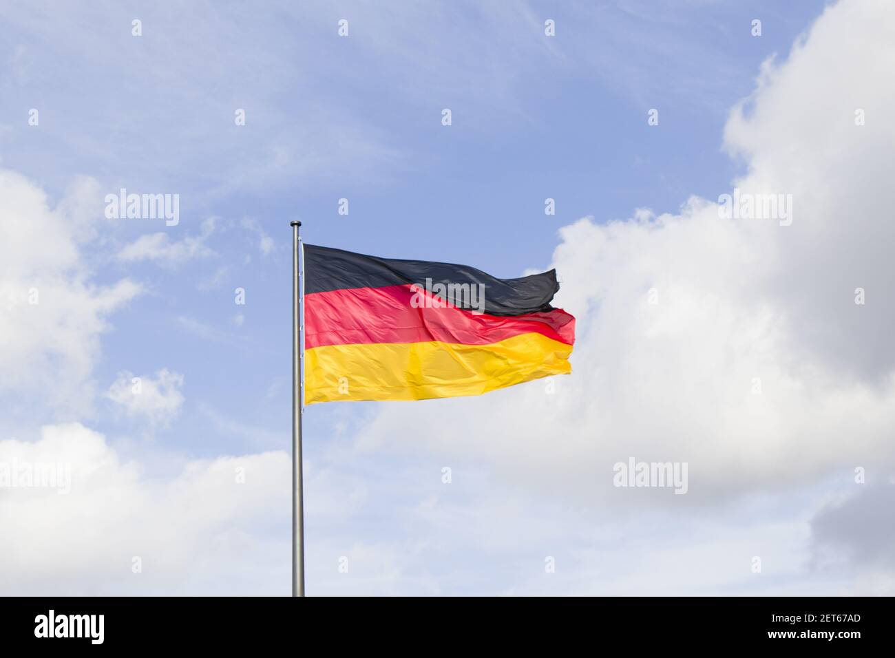 A German national flag, red, black, and yellow colors on the blue sky background Stock Photo Alamy