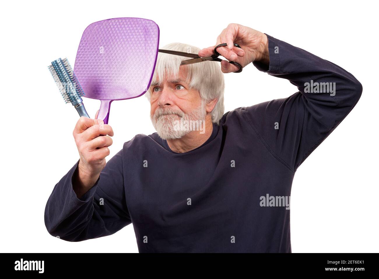 Horizontal shot of an old man giving himself a pandemic haircut.  White background. Stock Photo