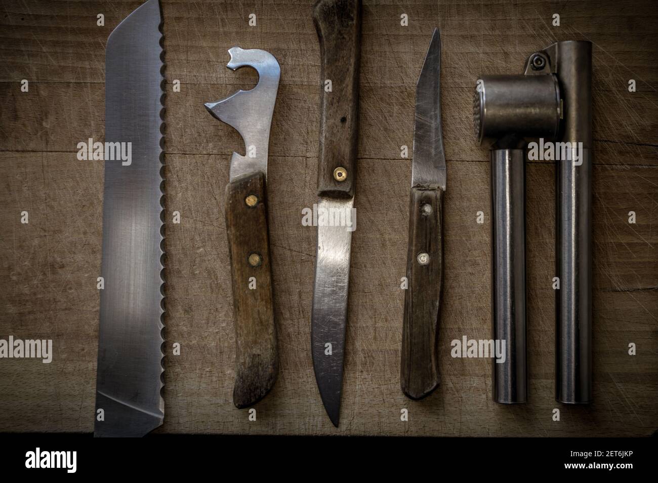A top view of a set of kitchen knives with wooden handles and a garlic ...