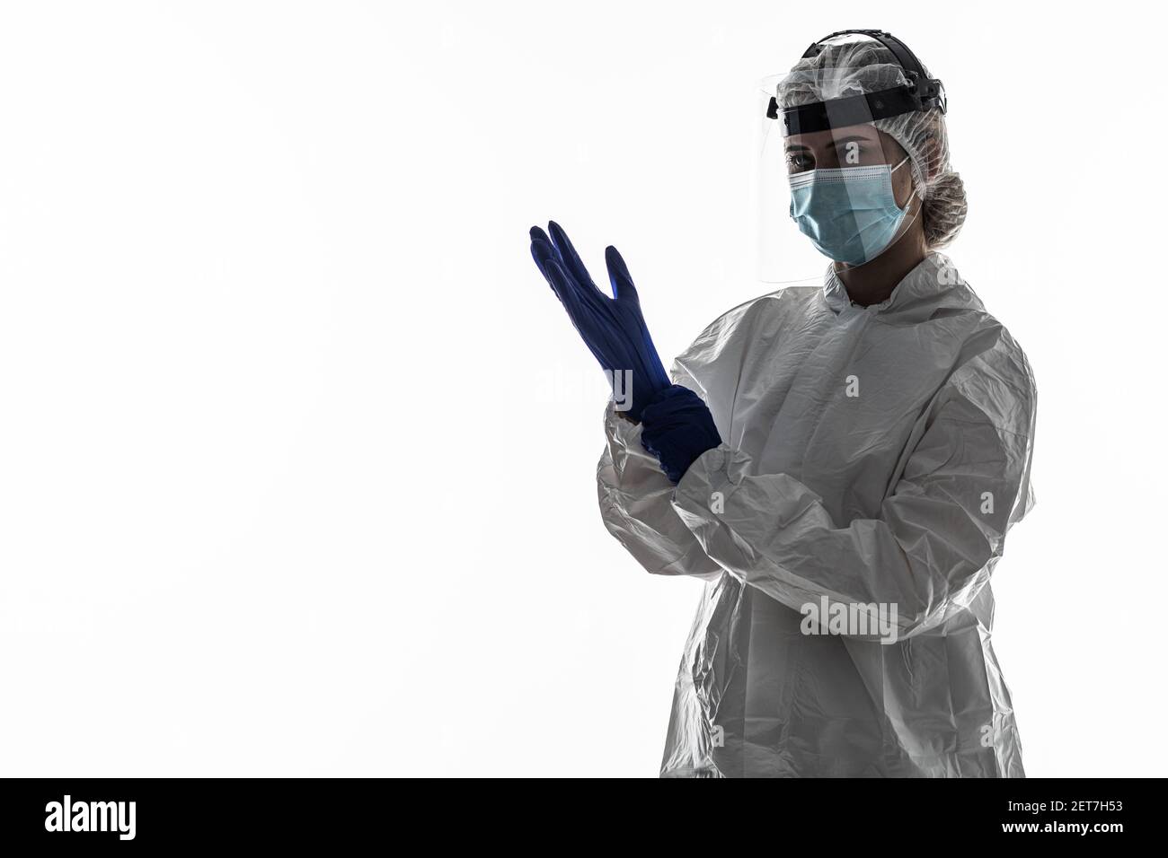 Woman wearing gloves with biohazard chemica protective suit on white background. Stock Photo