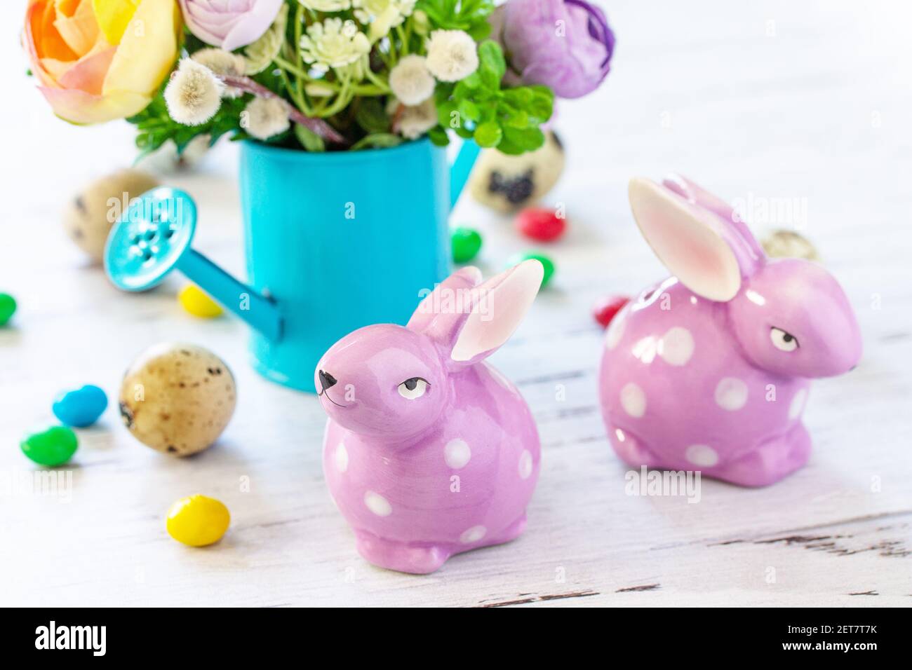 Happy Easter background with spring flowers, easter eggs, sweets and easter bunny on a white wooden background. Stock Photo