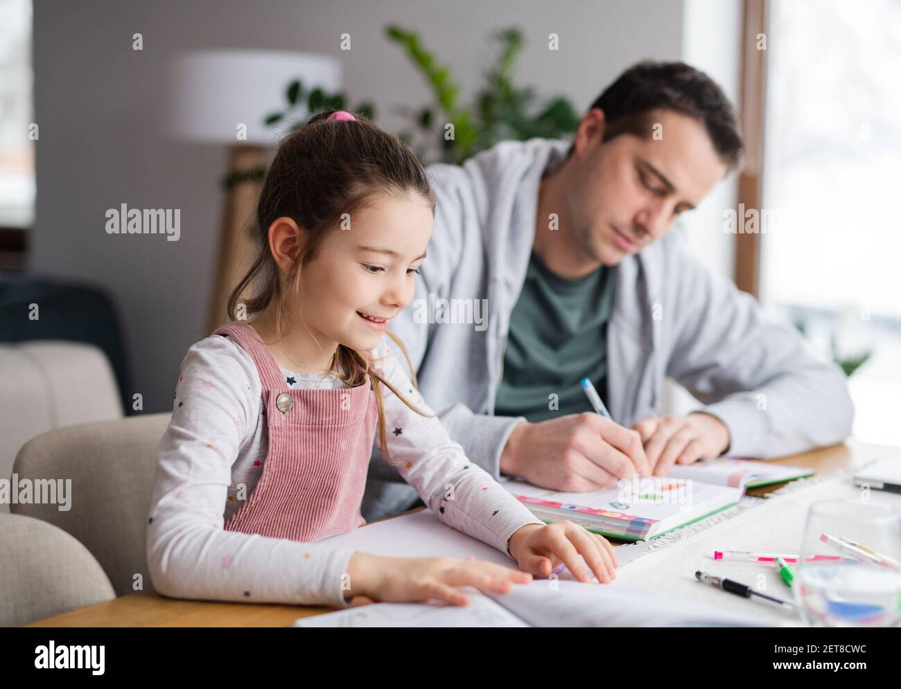 Father helping daugther with homework indoors at home, distance learning. Stock Photo
