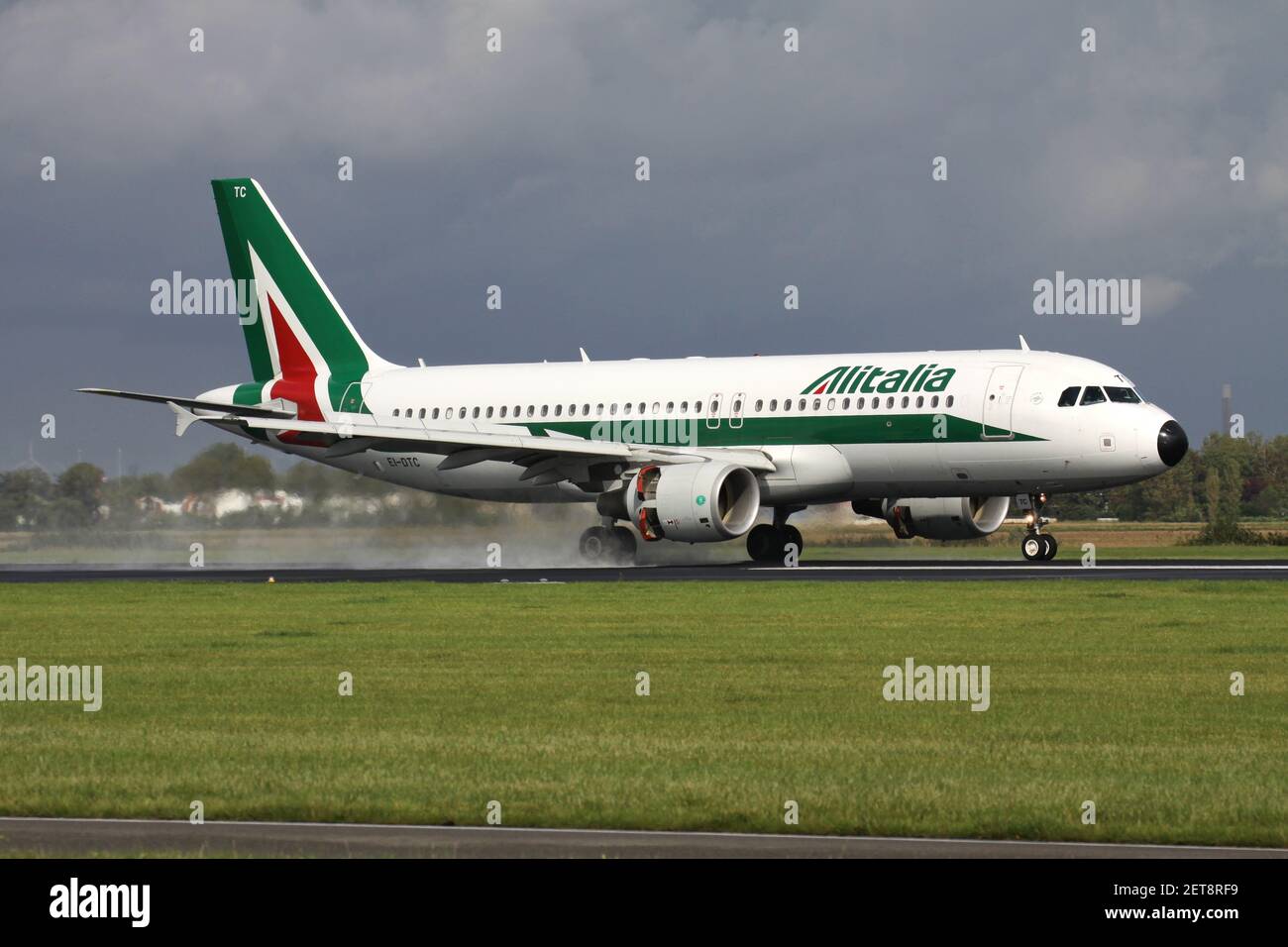 Italian Alitalia Airbus A320-200 with registration EI-DTC just landed on runway 18R (Polderbaan) of Amsterdam Airport Schiphol after a rain shower. Stock Photo