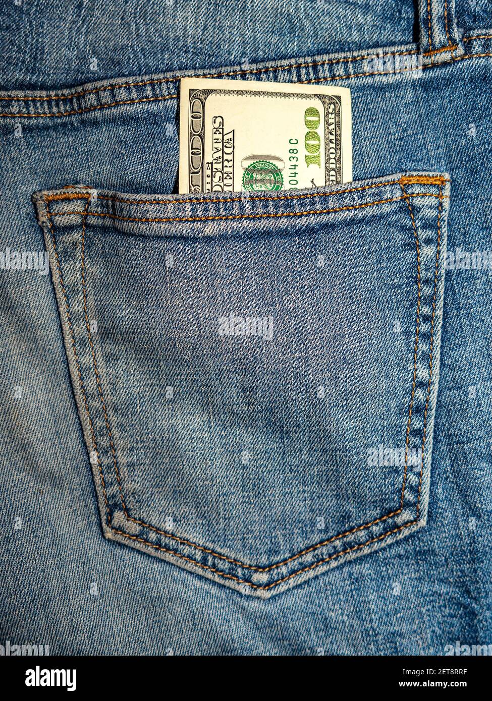 a hundred-dollar bill sticks out of the back pocket of his blue jeans. Stock Photo