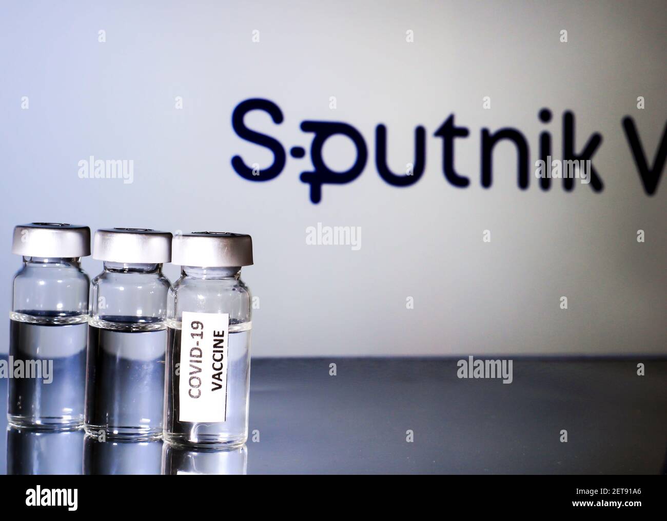 Madrid, Spain- February 23, 2021: Glass vials with covid-19 vaccine on white background. Sputnik V logo in the background. Stock Photo